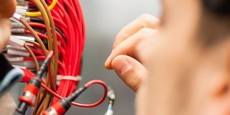 Ein Elektroniker und Kabel aus einem Verteilerkasten